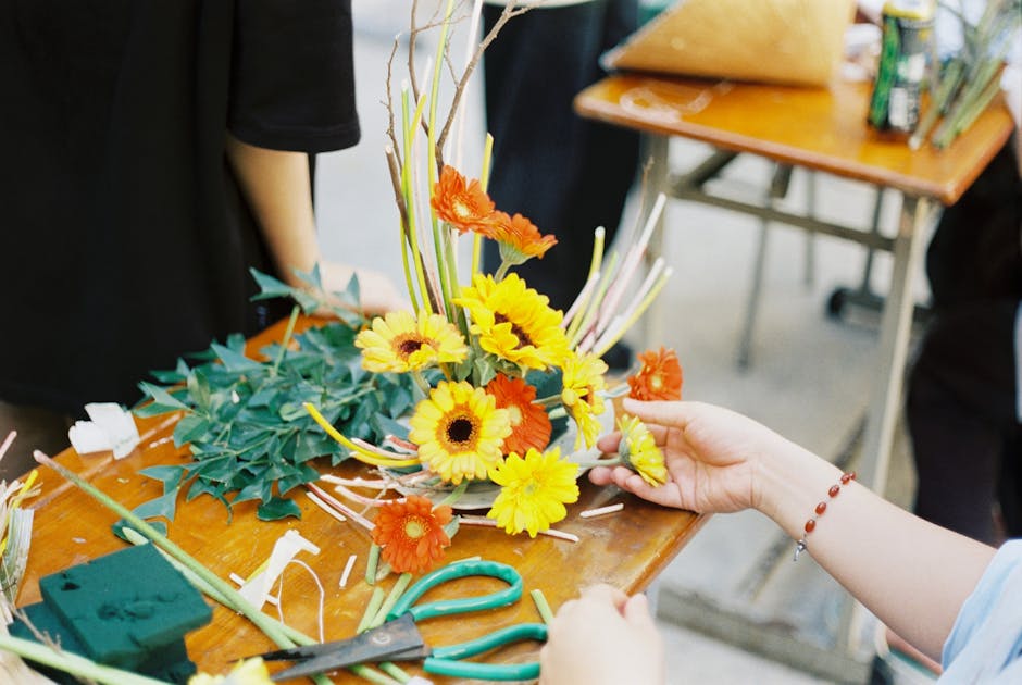 Close-up of a colorful flower arrangement in progress on a wooden table, showcasing vibrant blooms.